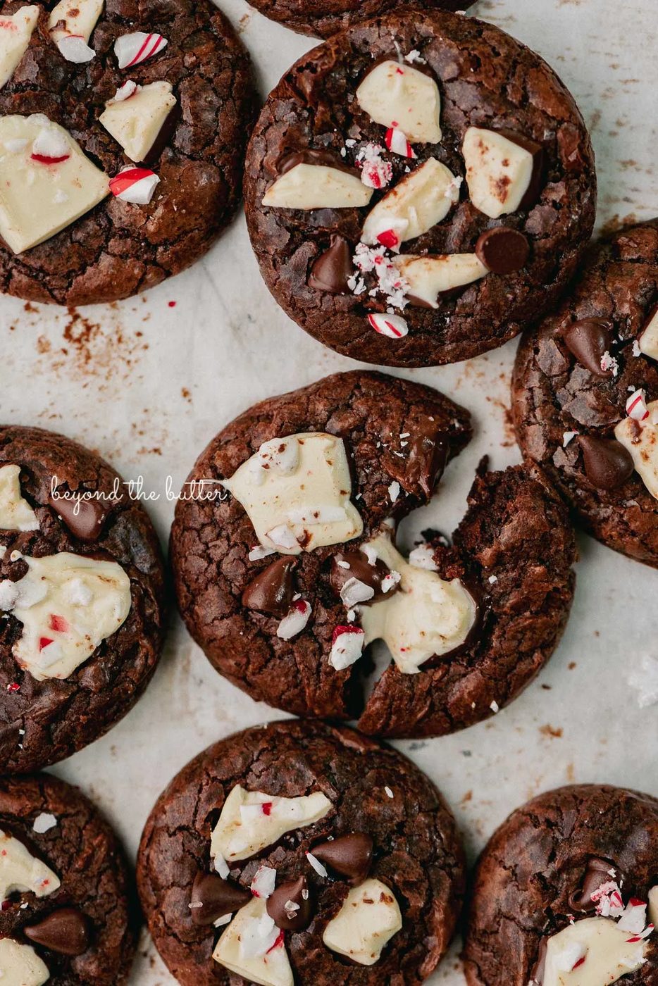 Just baked peppermint bark brownie crinkle cookies on a parchment paper lined baking sheet | © Beyond the Buter