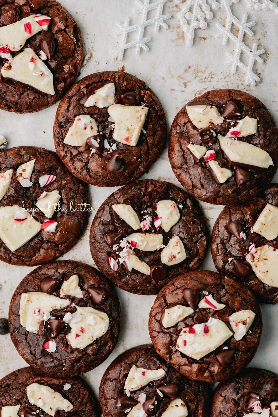 Just baked peppermint bark brownie crinkle cookies on a parchment paper lined baking sheet | © Beyond the Buter
