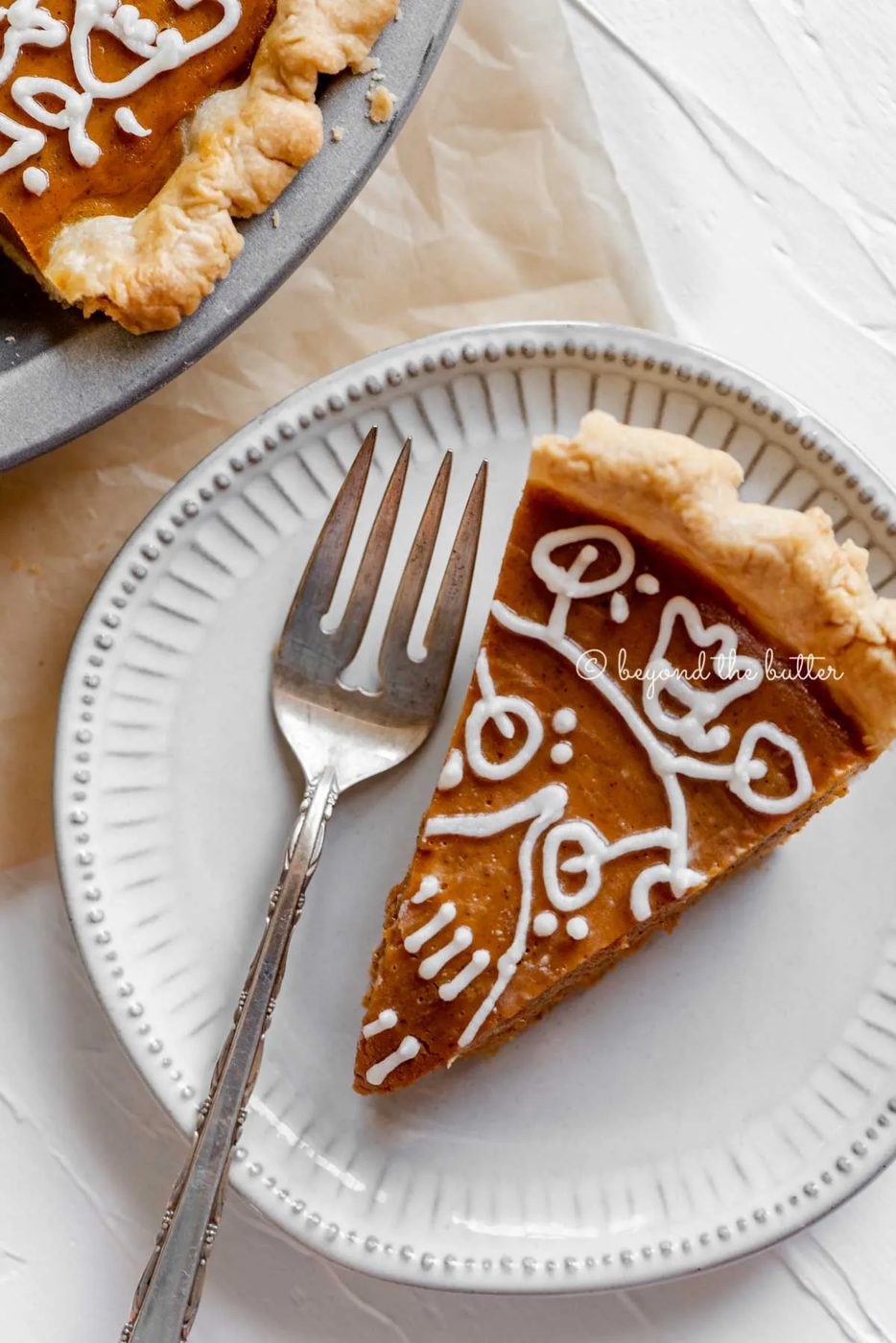 Slice of pumpkin pie on a dessert plate with a fork resting on the plate and pie plate off to the side | All Images © Sovuh