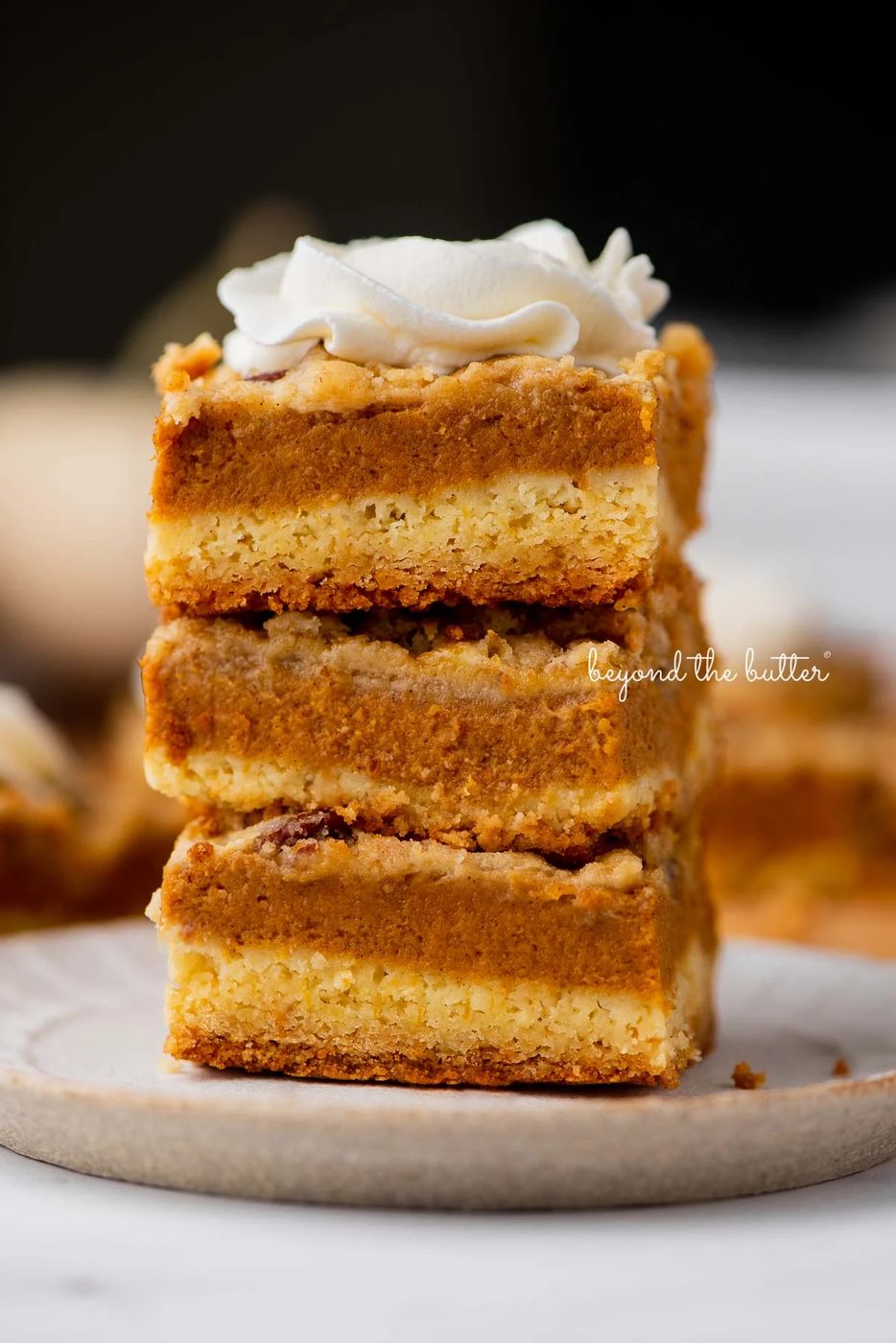Stack of three pumpkin pie cake bars on a parchment paper lined bottom | © Sovuh