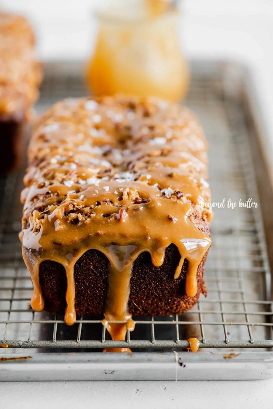 Angled image of salted caramel banana nut bread loaves on a wire cooling rack with caramel drizzled over the top | All Images © Sovuh