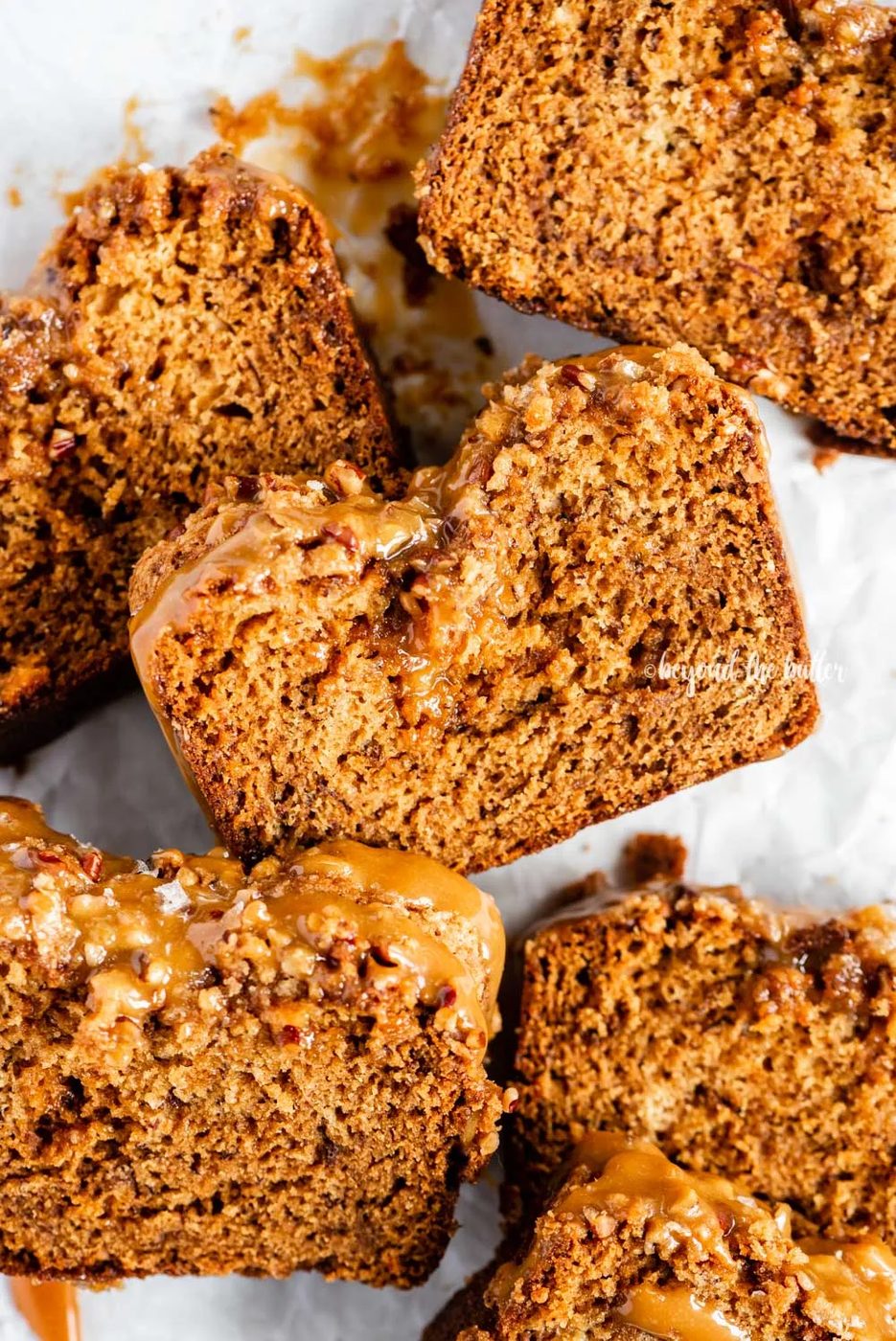 Closeup overhead image of slices of salted caramel banana nut bread on parchment paper | All Images © Sovuh