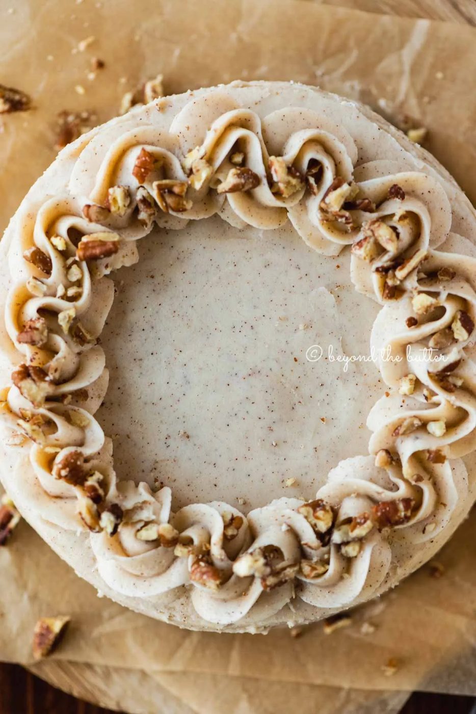 Overhead closeup image of 6 inch carrot cake frosted on sheets of brown parchment paper | All Images © Sovuh