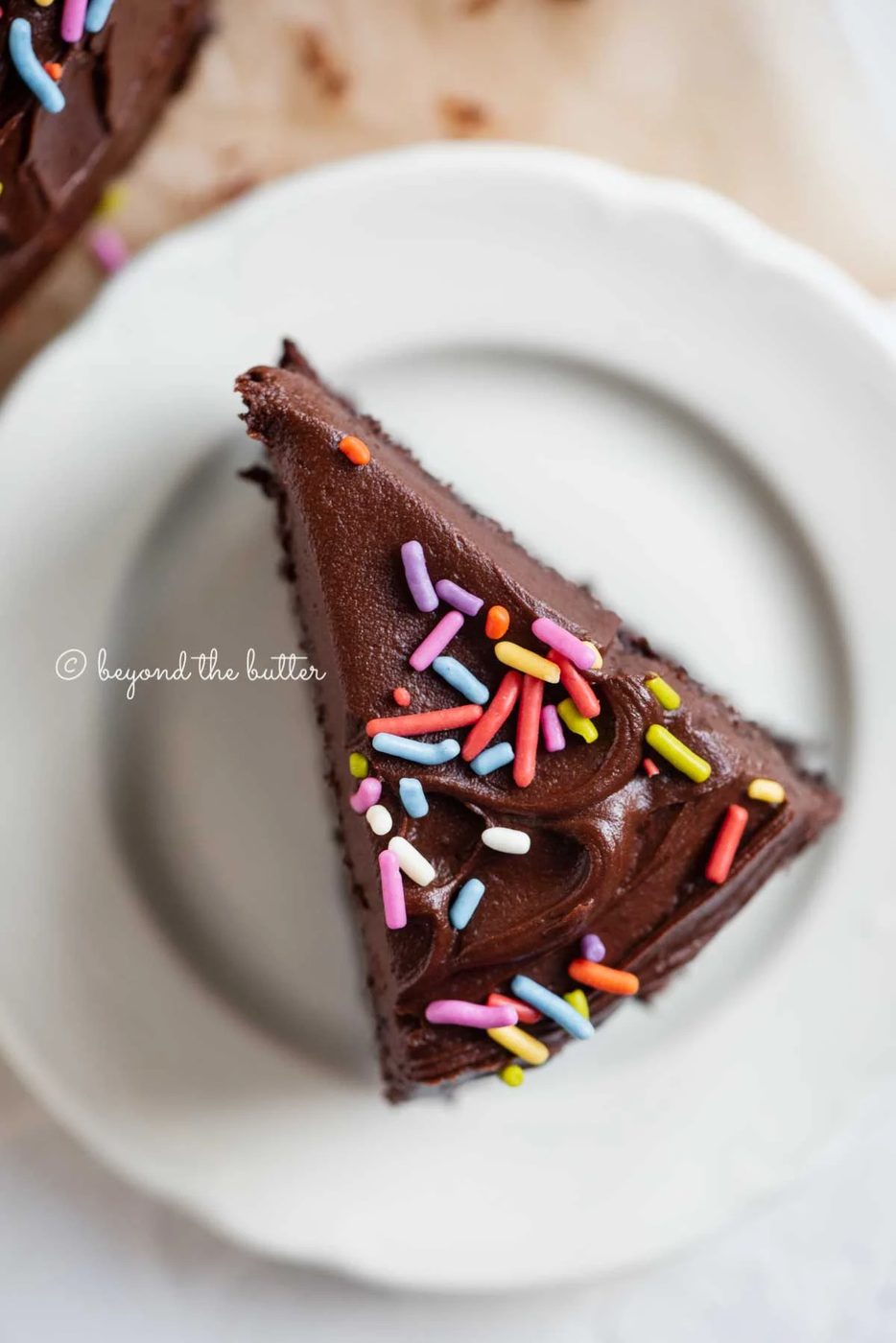 Overhead closeup image of single slice of 6 inch chocolate cake on white dessert plate | All Images © Sovuh