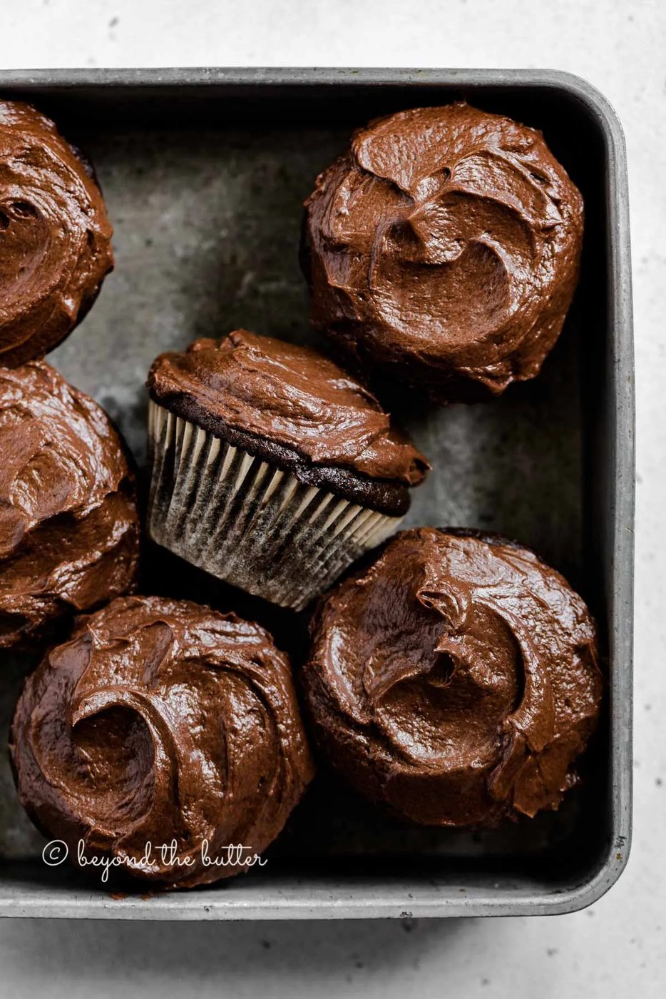 Overhead image of small batch chocolate cupcakes in vintage metal baking tin with one on its side | All Images © Sovuh