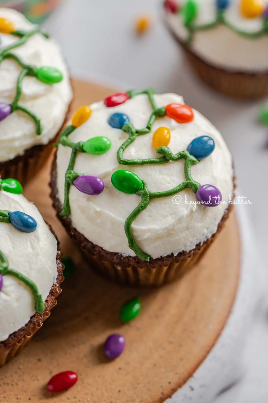 Small batch of gingerbread cupcakes on an upside down pie plate on a white background with scattered chocolate covered sunflower seeds | All Images © Sovuh