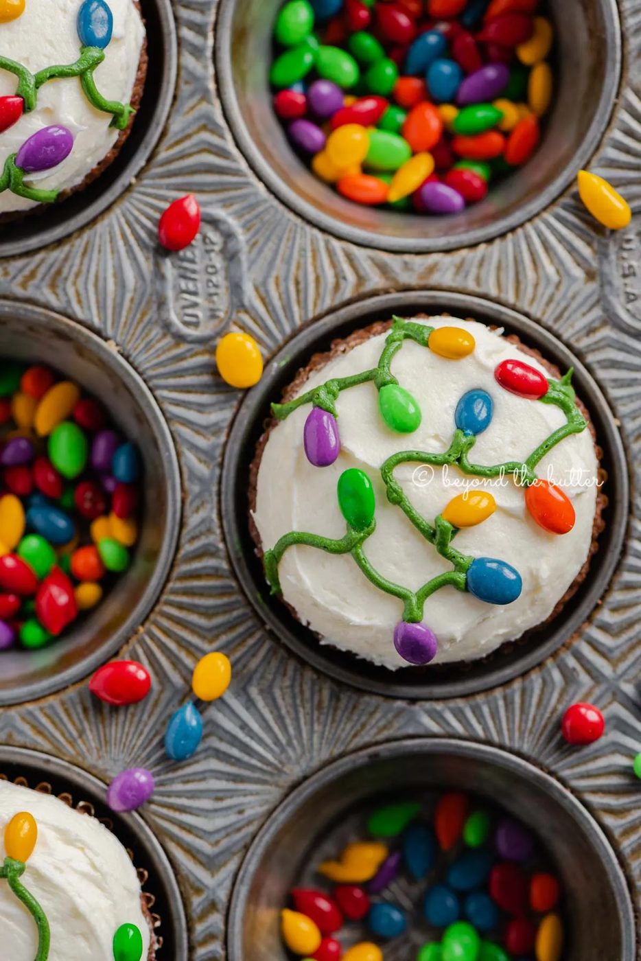 Cupcake tin with decorated small batch gingerbread cupcakes with marshmallow frosting and rainbow chocolate covered sunflower seeds | All Images © Sovuh