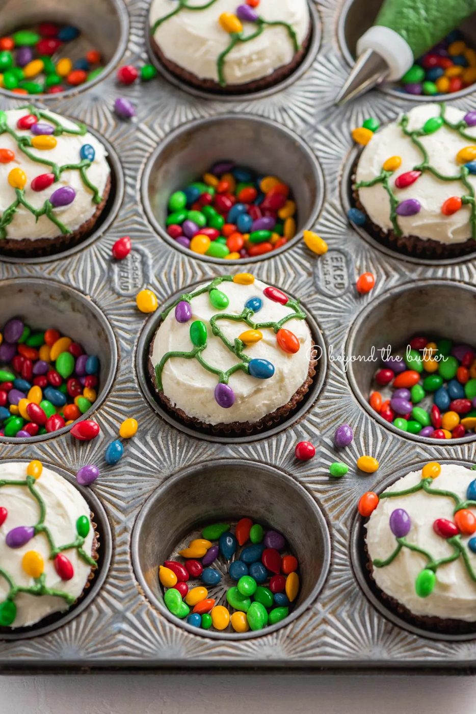 Cupcake tin with decorated small batch gingerbread cupcakes with marshmallow frosting and rainbow chocolate covered sunflower seeds | All Images © Sovuh