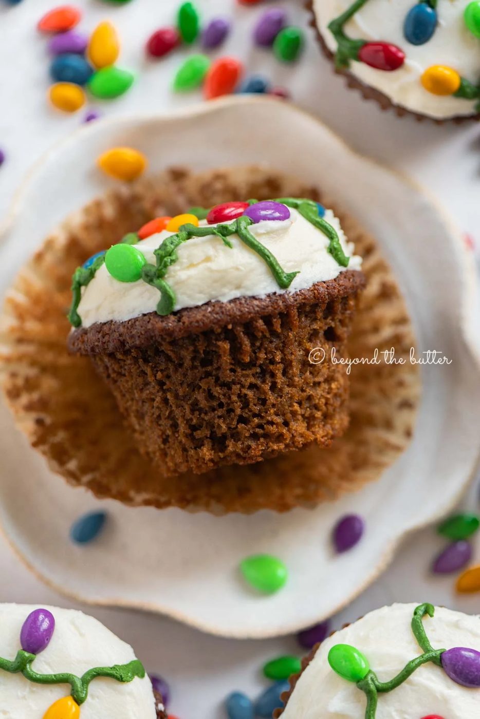 Liner removed gingerbread cupcake on a small dessert plate on a white, chocolate covered sunflower seed background | All Images © Sovuh