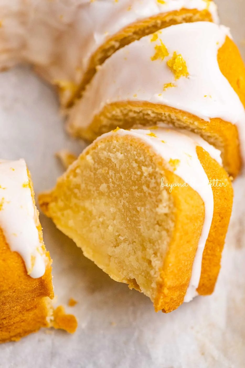 Sliced lemon cream cheese pound cake on white parchment paper | © Sovuh