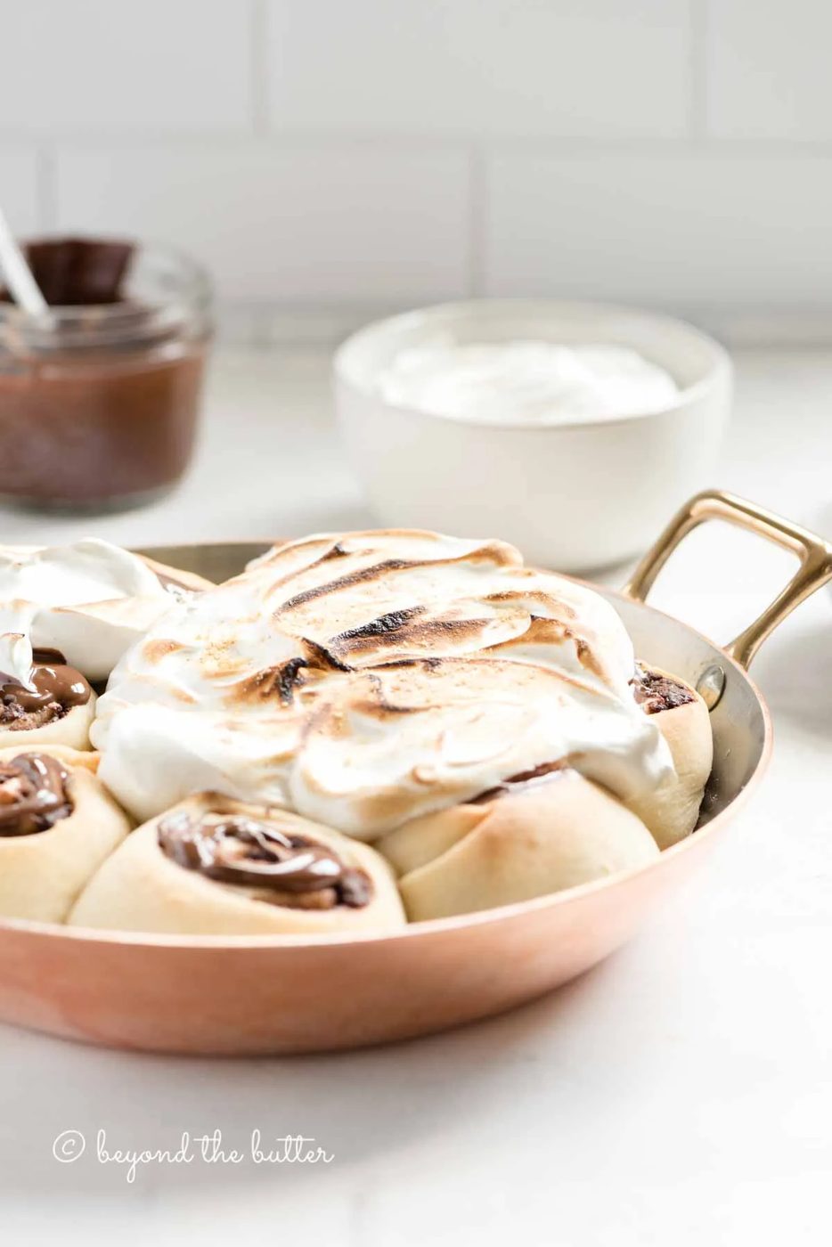Pan of s'mores rolls on a kitchen counter with bowl of marshmallow topping and melted chocolate | All Images © Sovuh