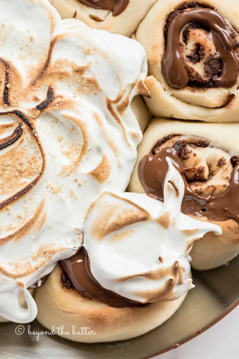 Overhead closeup image of s'mores rolls partially covered with marshmallow topping | All Images © Sovuh
