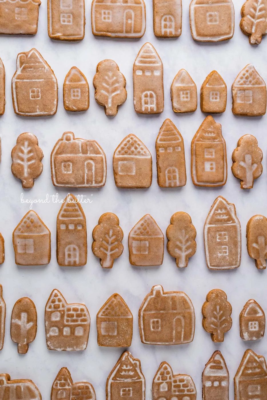 Cut out gingerbread cookies lined up in rows on a white marbled background | © Sovuh, LLC