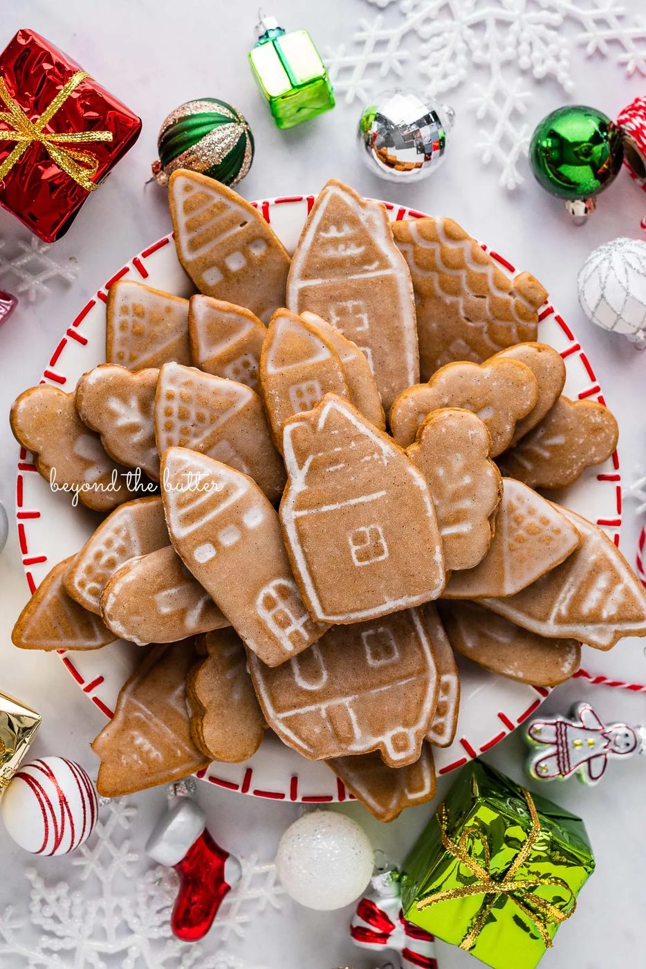Christmas themed dessert plate filled with soft and chewy gingerbread cookies with ornaments around it on a white marbled background | © Sovuh