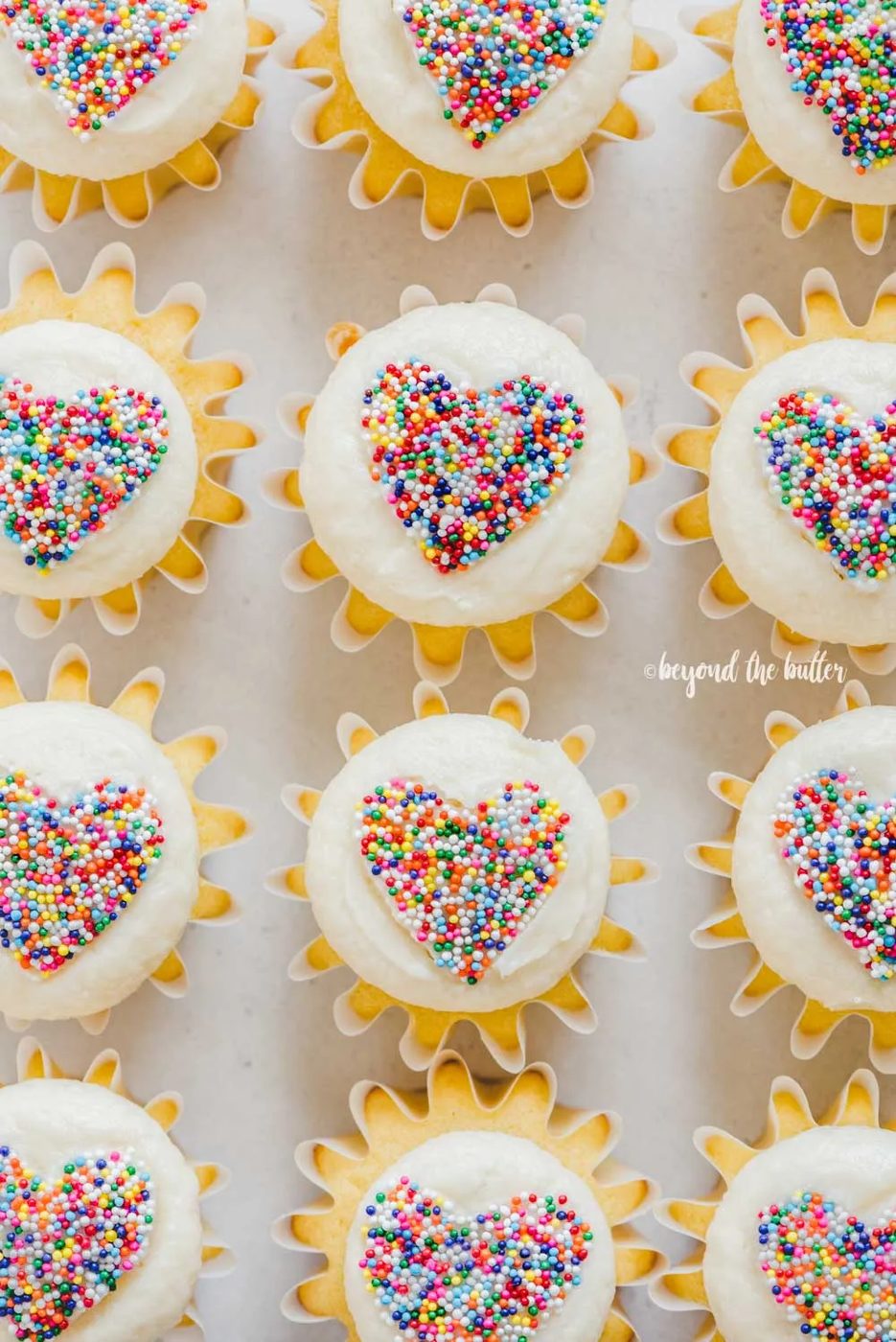 Overhead image of sprinkled heart cupcakes on white/grya background | All Images © Sovuh