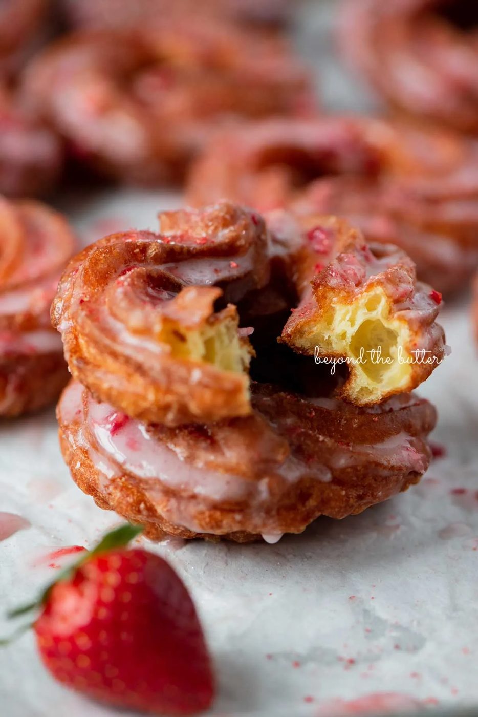 Light and airy stacked strawberry glazed french crullers with cite taken out of the top cruller | © Sovuh