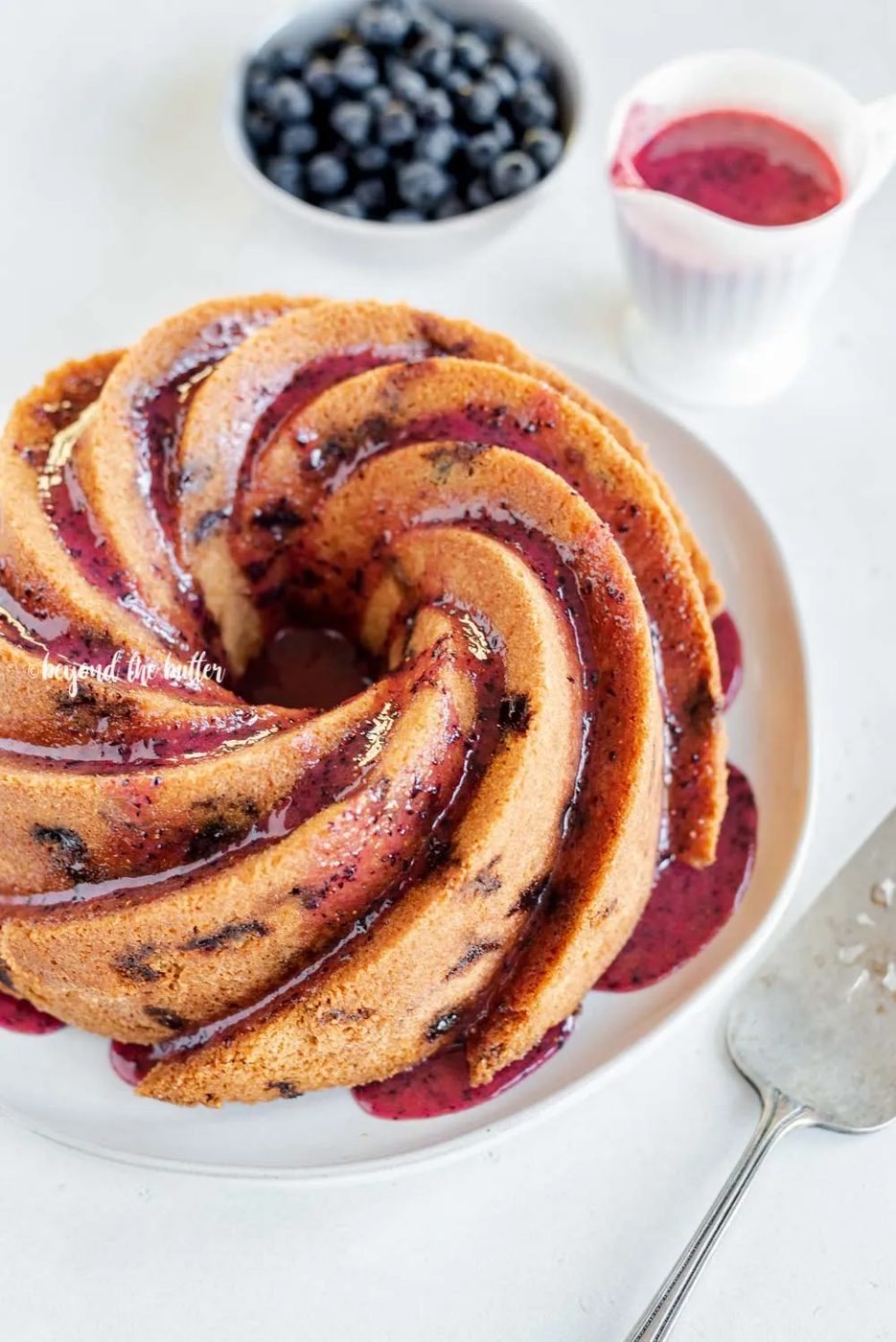 Angled image of straightforward blueberry bundt cake with blueberry glaze drizzled over the top | All Images © Sovuh, LLC