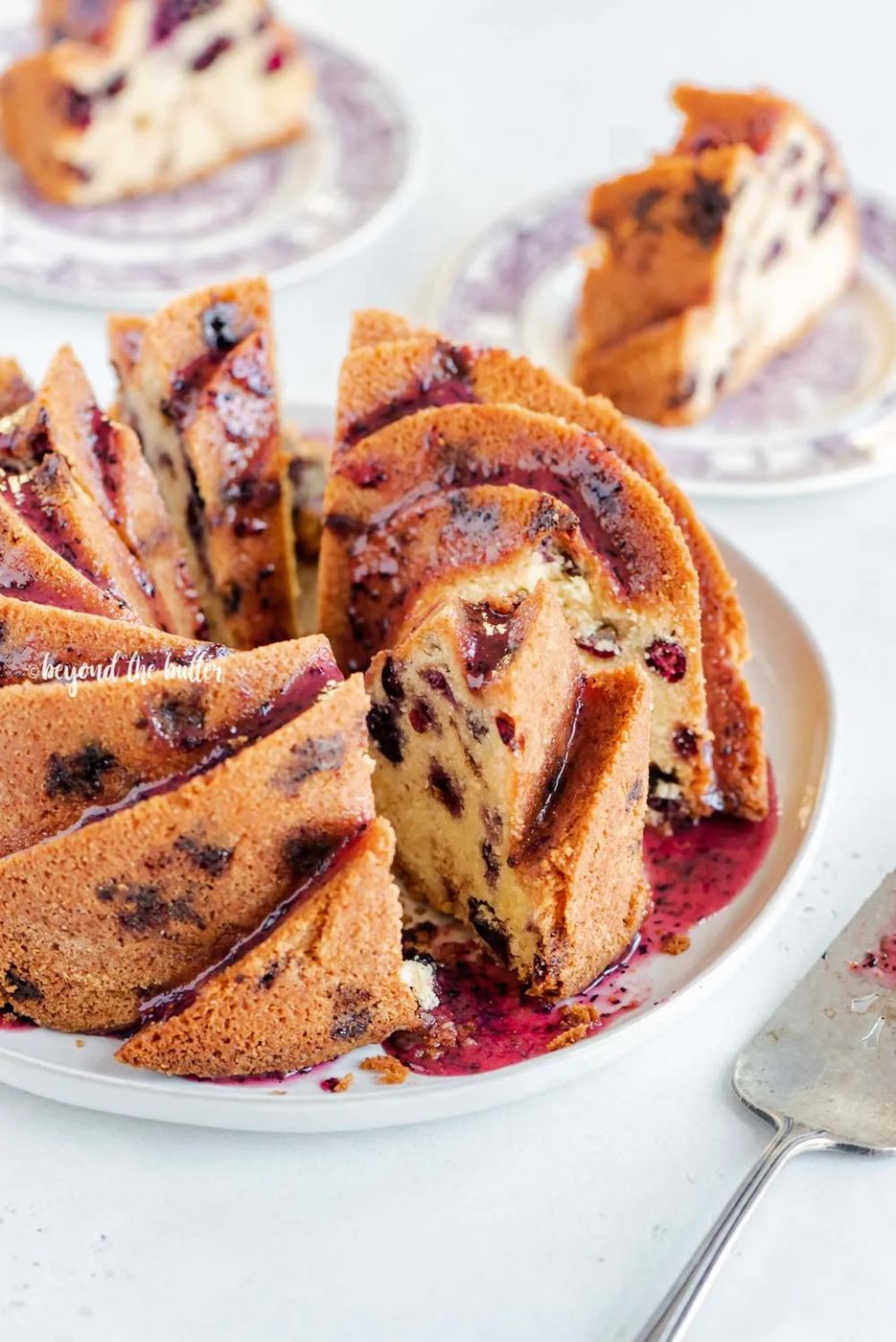 Angled image of sliced blueberry bundt cake with blueberry glaze drizzled over the top | All Images © Sovuh, LLC