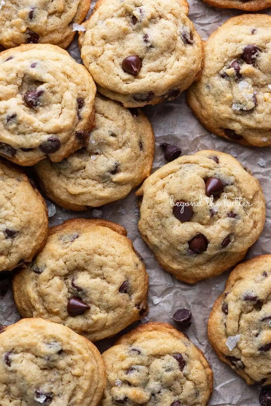 Chocolate chip pudding cookies randomly placed on a piece of crumbled parchment paper.