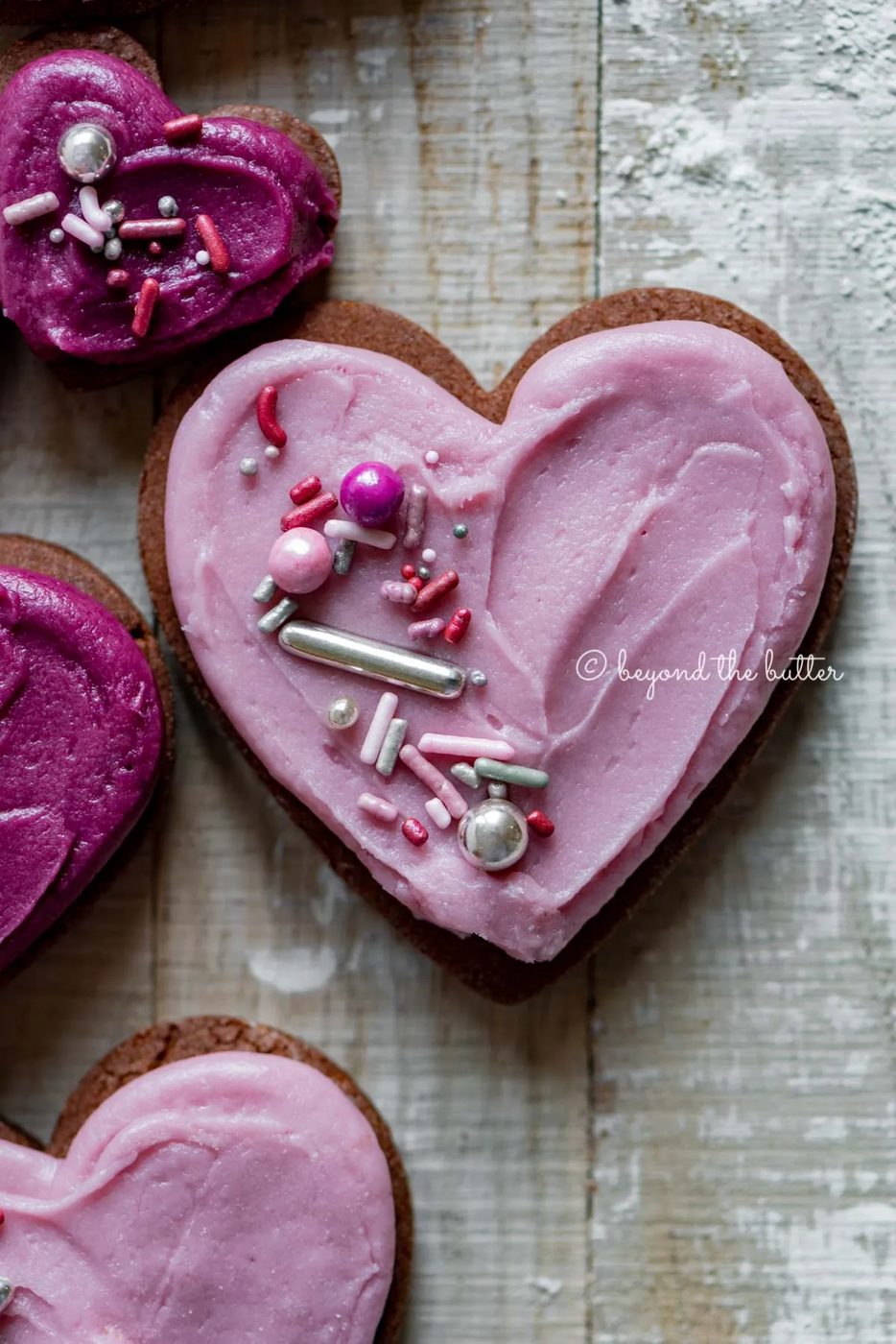 Closeup of decorated chocolate cut out sugar cookies on a light wood colored background | All Images © Sovuh