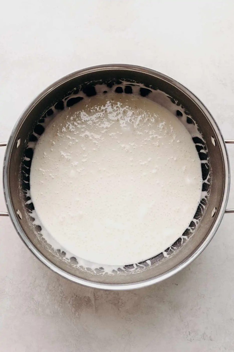 Melted mini marshmallows in a large nonstick stockpot on a white and grey marbled background.