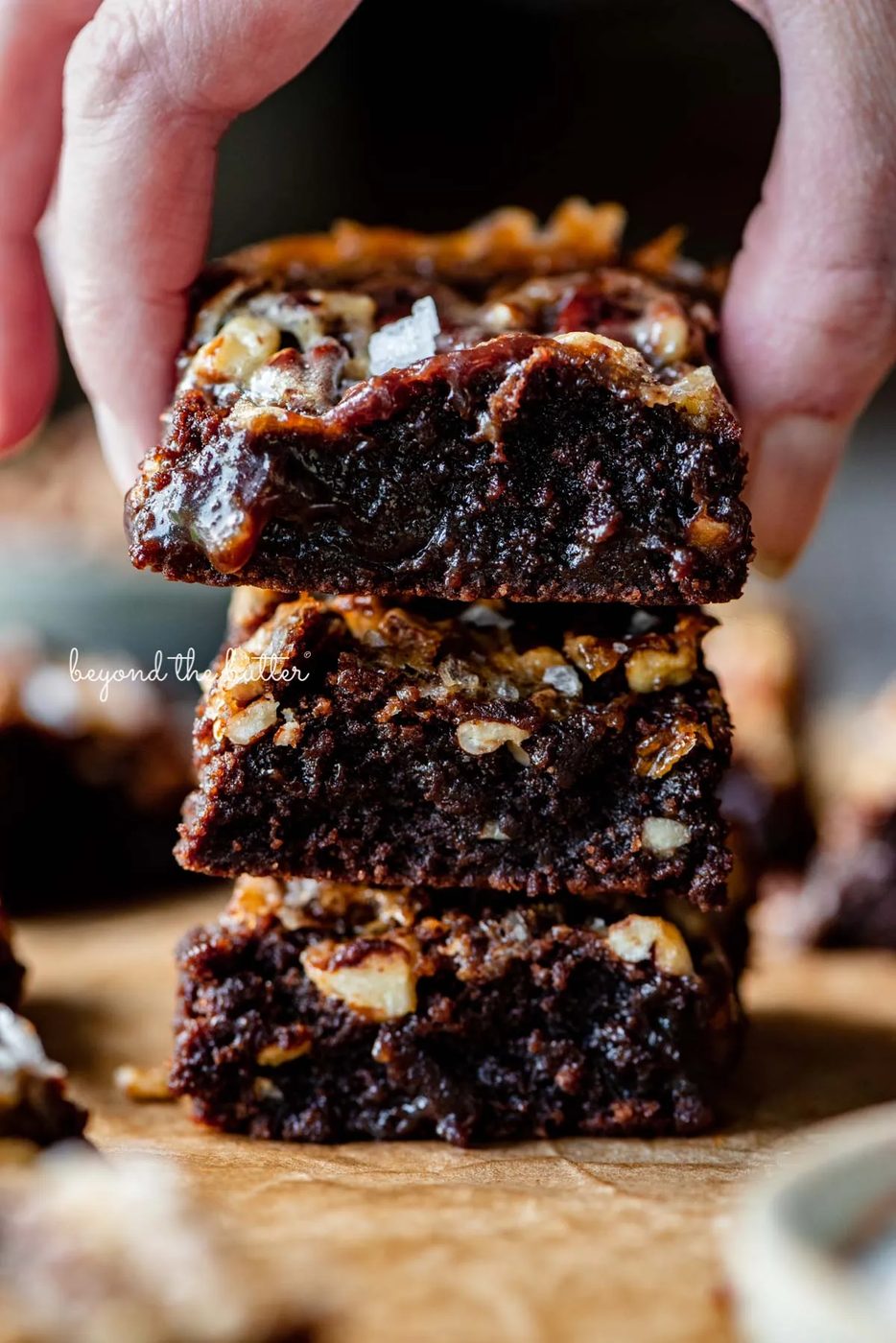 Stacking the best salted pecan pie brownies on brown parchment paper | © Sovuh