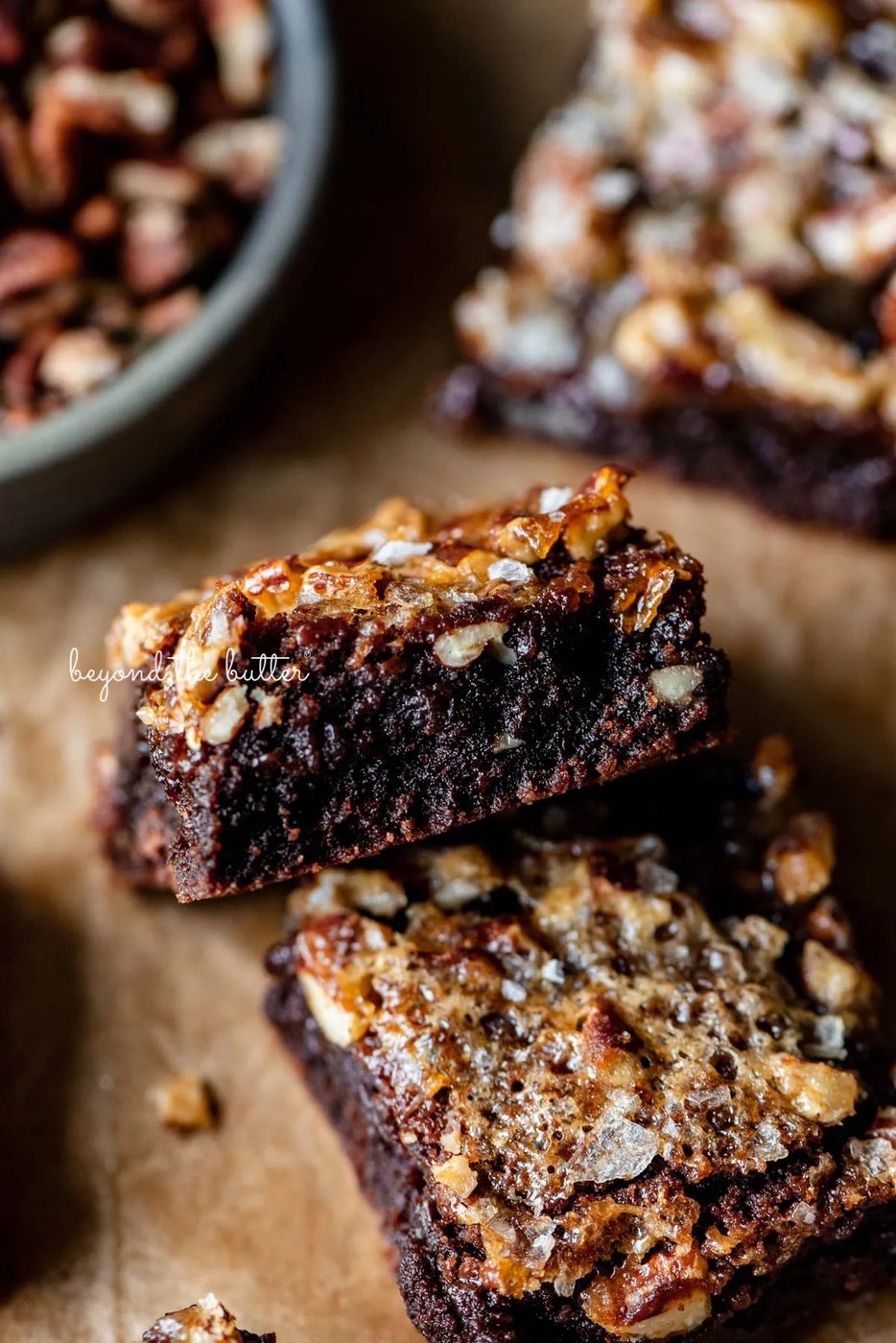 Semi-stacked salted pecan pie brownies on brown parchment paper | © Sovuh