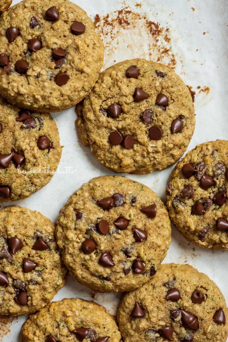 Zucchini chocolate chip oatmeal cookies on a parchment paper lined baking sheet from Sovuh.com | © Sovuh