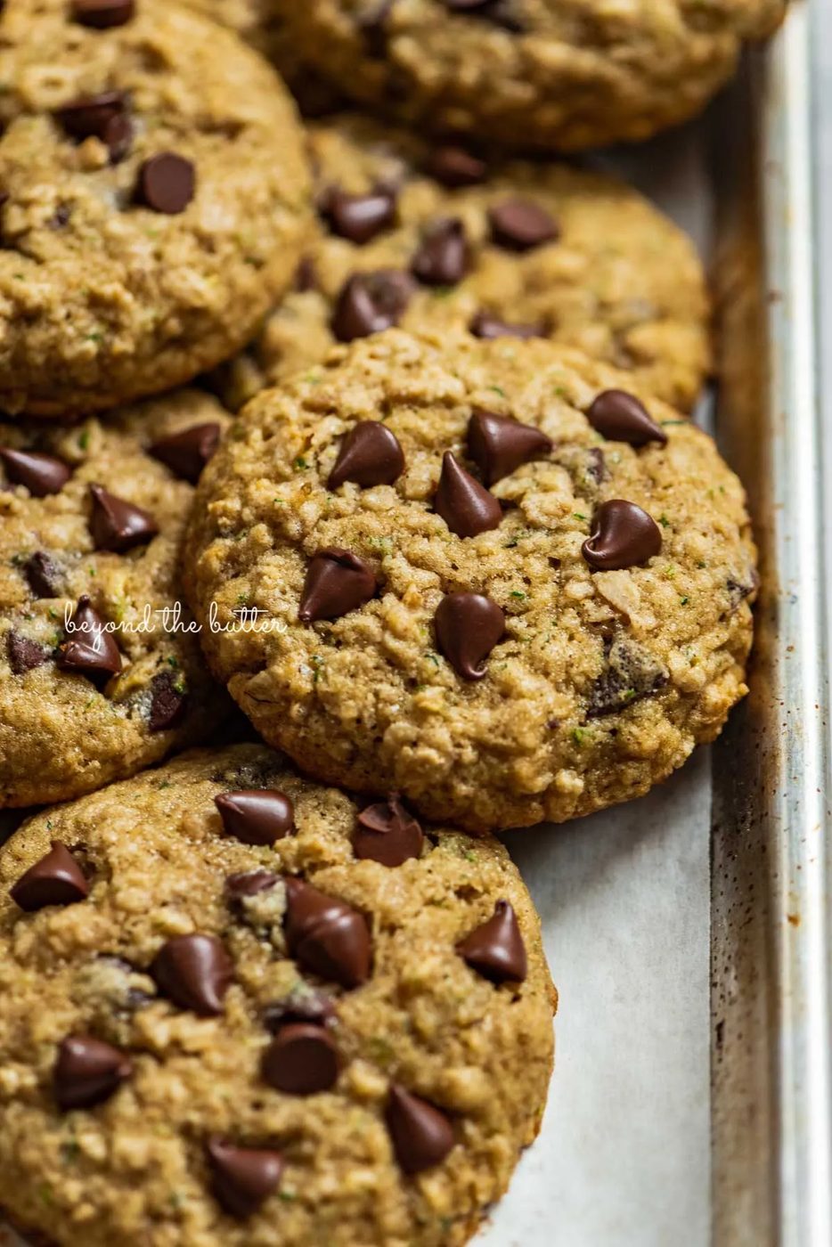 Zucchini chocolate chip oatmeal cookies on a parchment paper lined baking sheet from Sovuh.com | © Sovuh