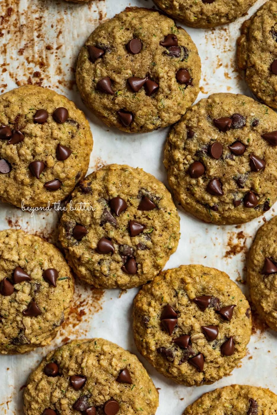 Zucchini chocolate chip oatmeal cookies on a parchment paper lined baking sheet from Sovuh.com | © Sovuh