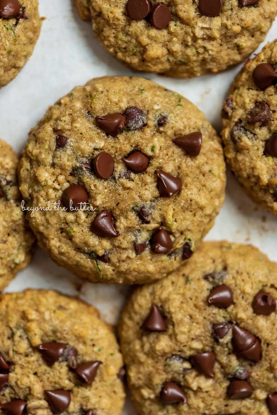 Zucchini chocolate chip oatmeal cookies on a parchment paper lined baking sheet from Sovuh.com | © Sovuh