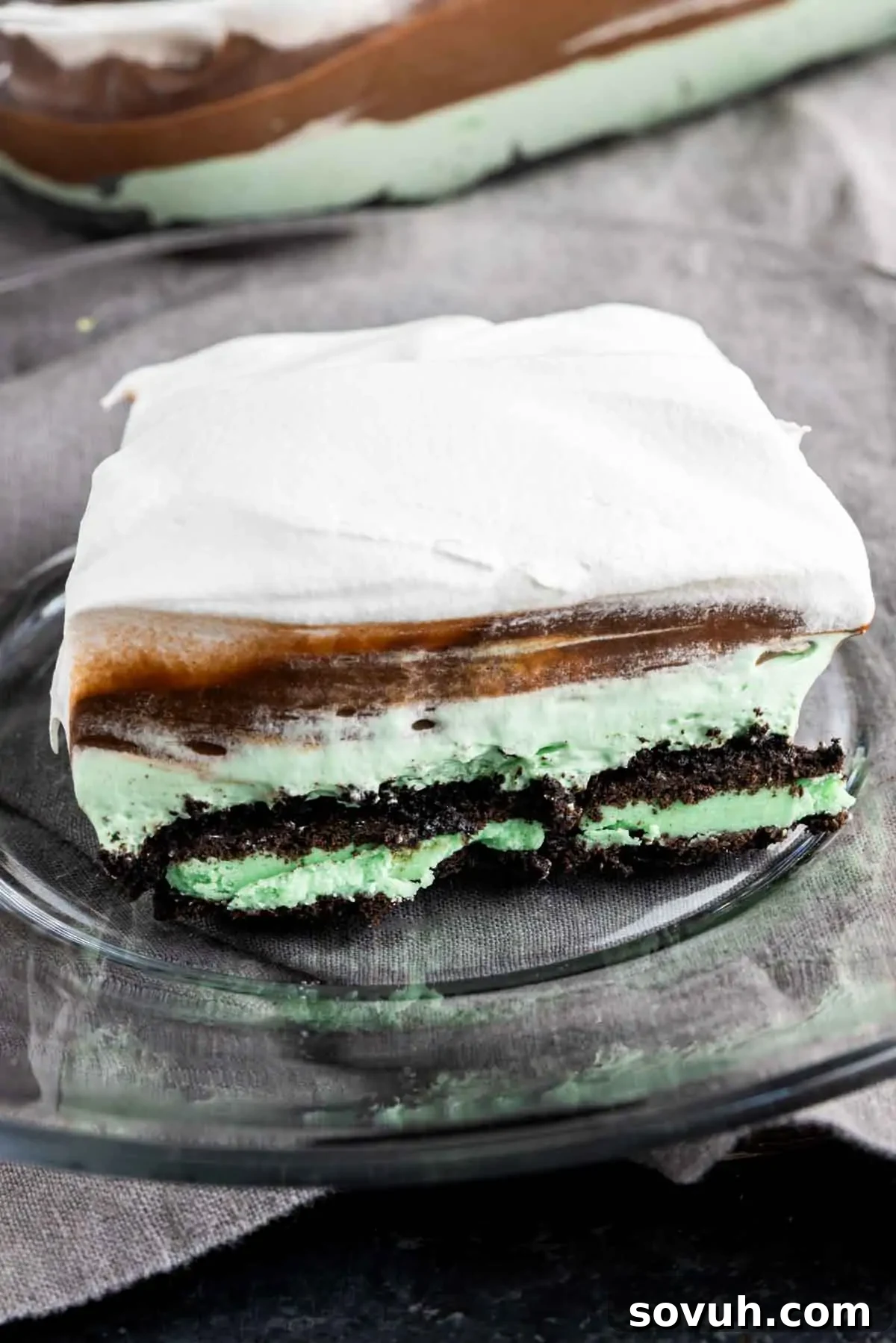 A perfectly sliced piece of Mint Oreo Dessert cake on a white plate, showcasing its distinct layers.