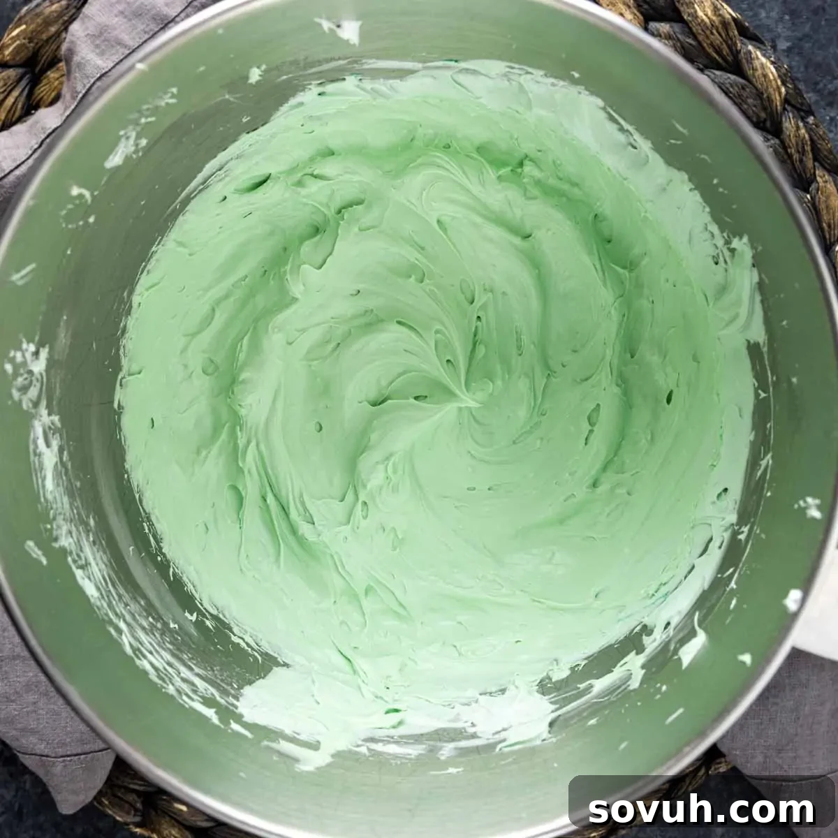 A shimmering bowl of vibrant green mint-flavored cream cheese and whipped topping mixture, ready for layering.