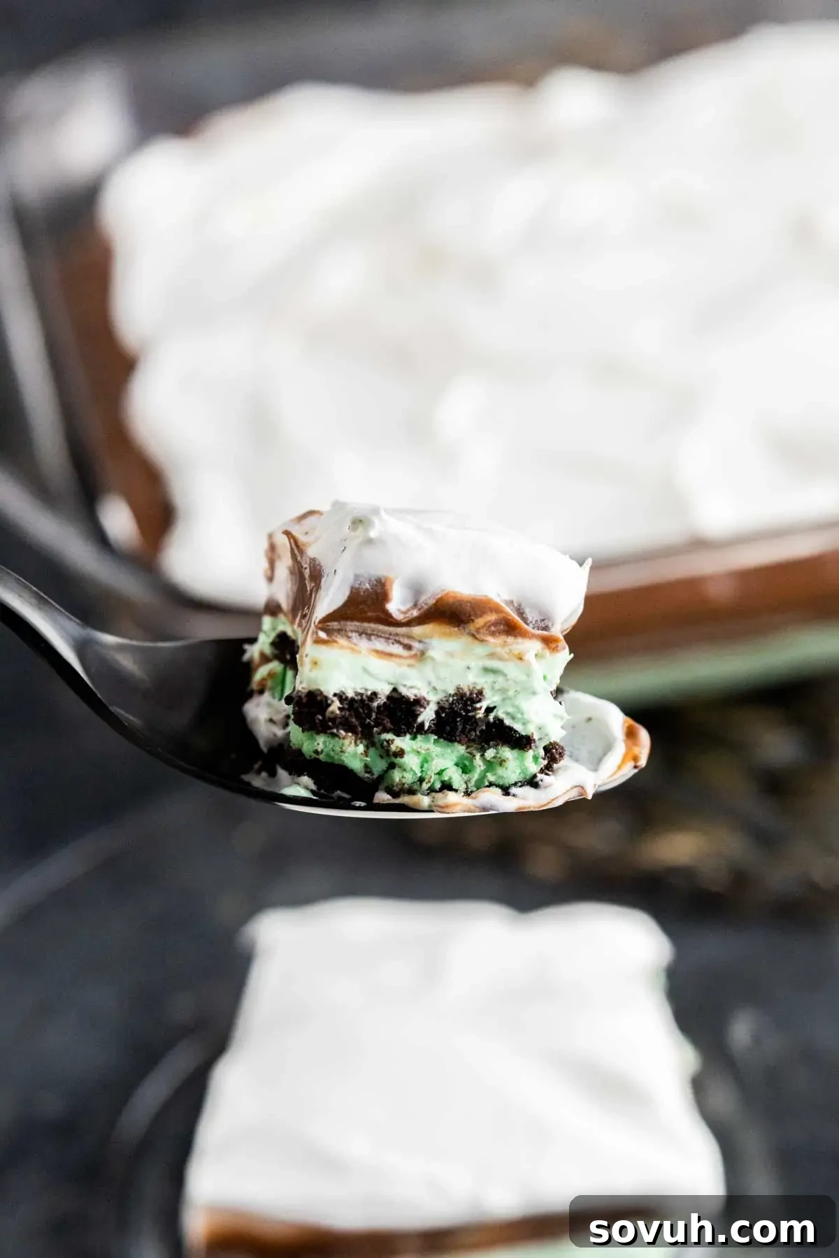 A close-up shot of a spoon scooping out a perfect bite of Mint Oreo Dessert, showing off its layered texture.