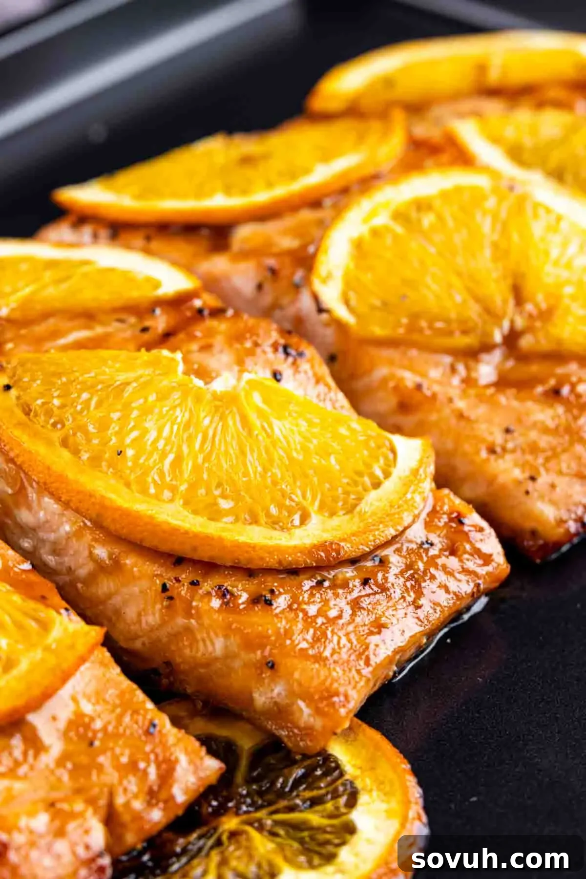 Citrus-Kissed Salmon 7 Orange Glazed Salmon topped with orange slices on a cooking surface.