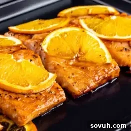 Citrus-Kissed Salmon 9 Orange Glazed Salmon topped with orange slices on a cooking pan.