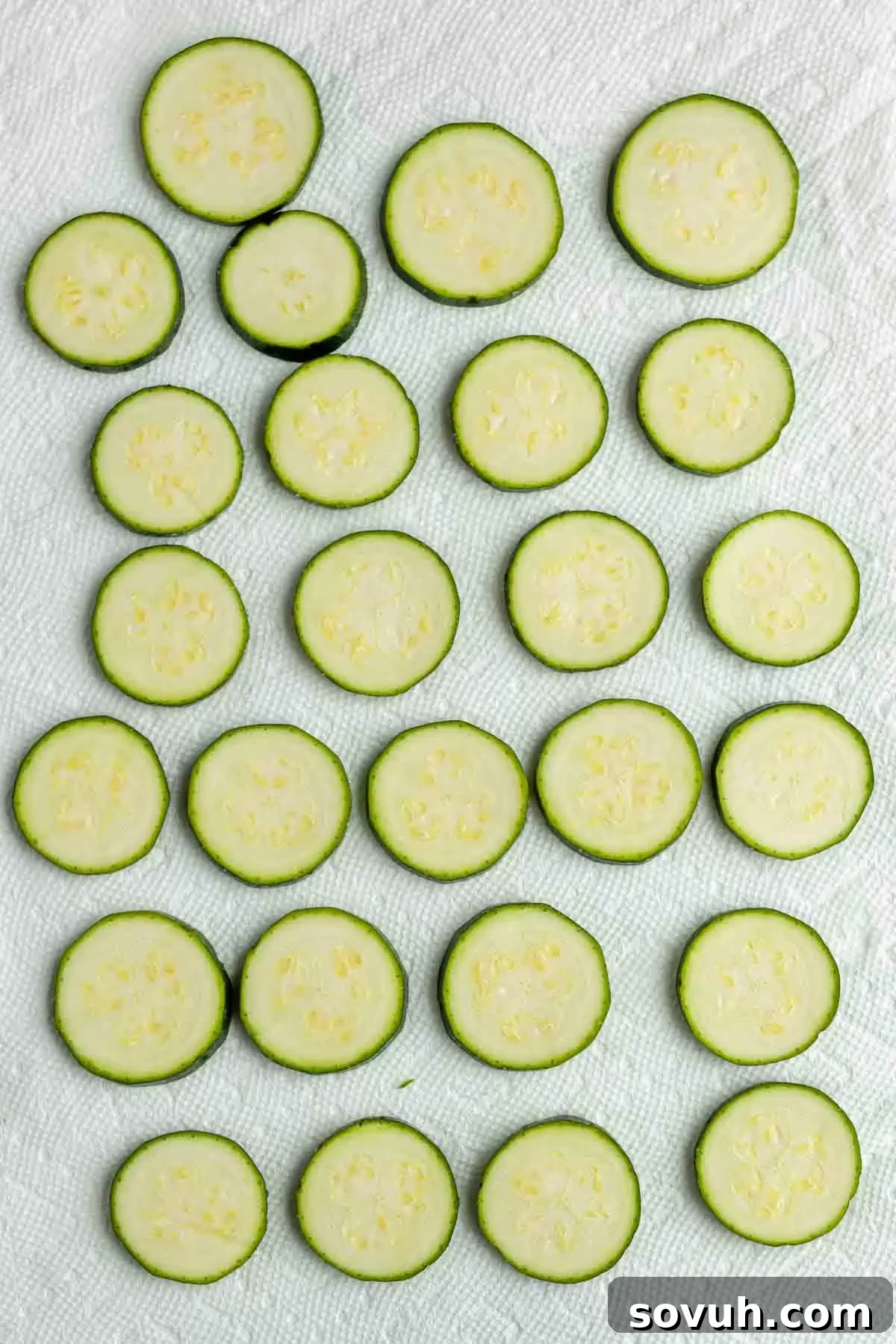 Zucchini slices drying on paper towels before frying.
