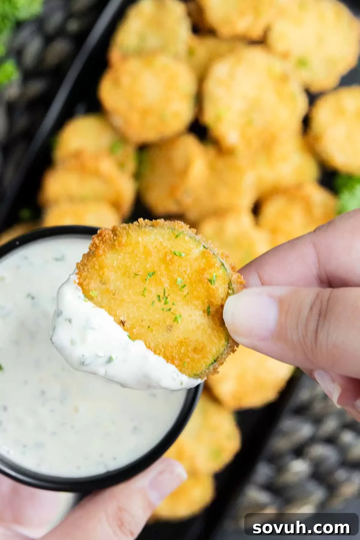 Zucchini Fritte being dipped into a bowl of lemon aioli.