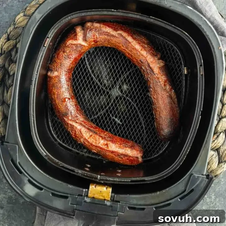 A cooked sausage in a black air fryer basket for Memphis Sausage and Cheese Platter