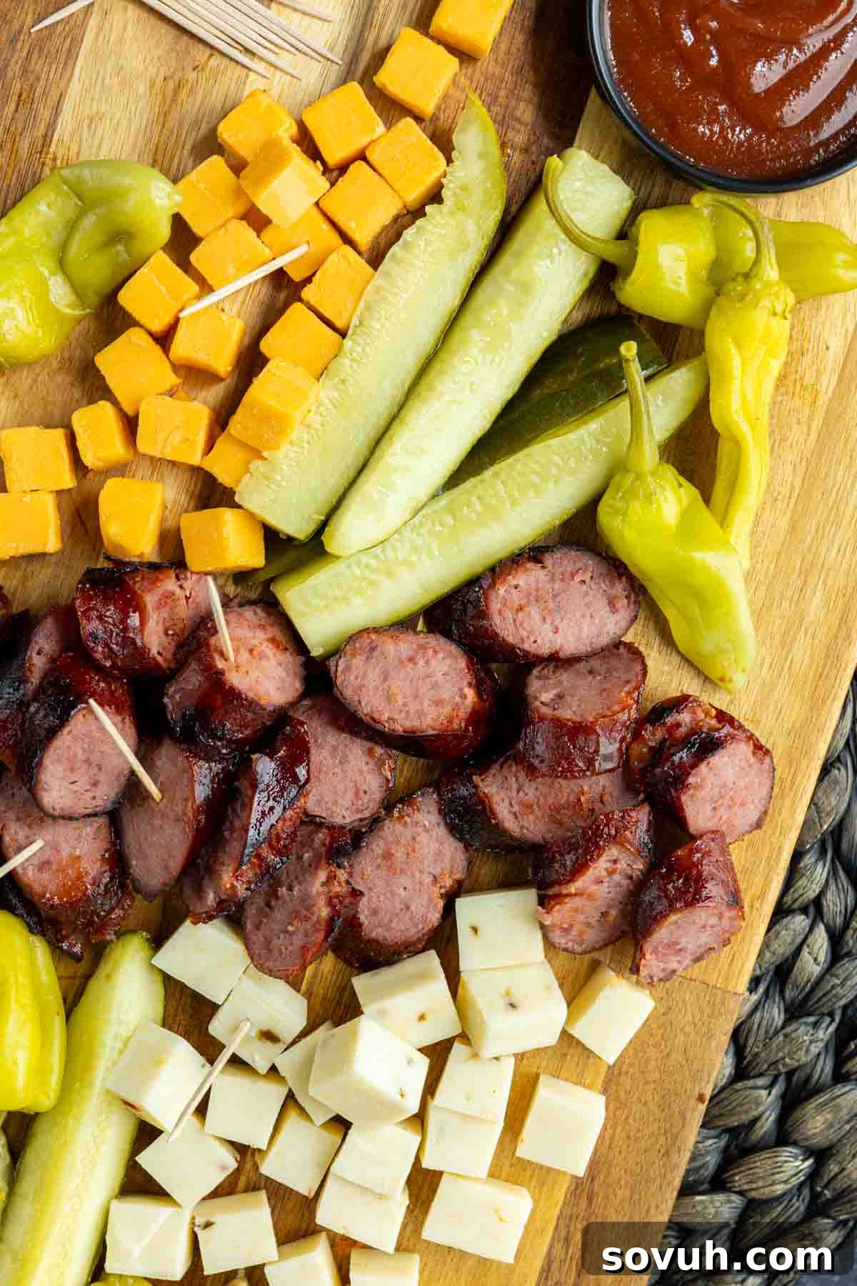 Memphis Sausage and Cheese Platter with cubed cheddar cheese, pickles, pepperoncini, sliced sausage, cubed white cheese, and a bowl of sauce.