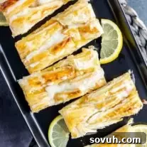 cut Lemon Cream Cheese Danish on black plate with fresh lemon slices