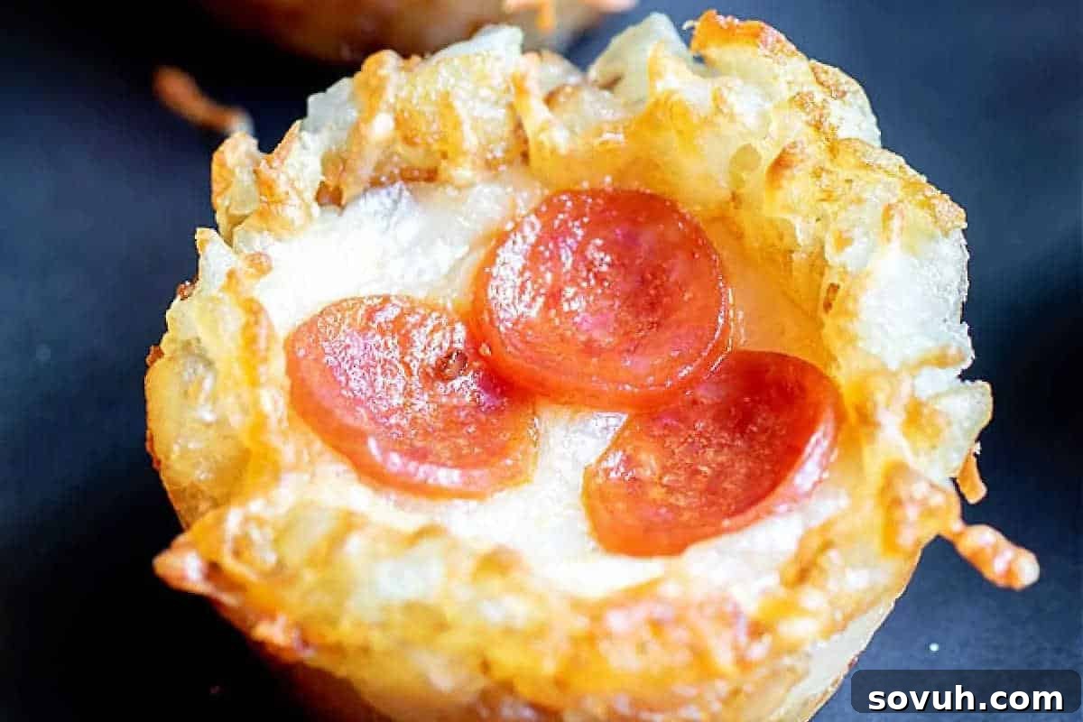 Close-up of a mini pizza with melted cheese, golden crust, and three slices of pepperoni on top.