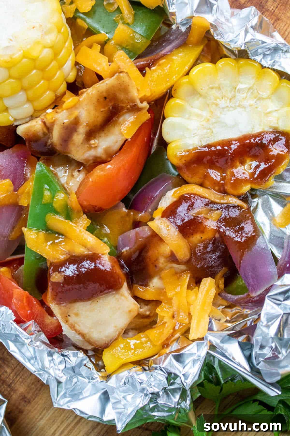 Grilled chicken, corn, bell peppers, and onions topped with barbecue sauce and melted cheese, served in foil.