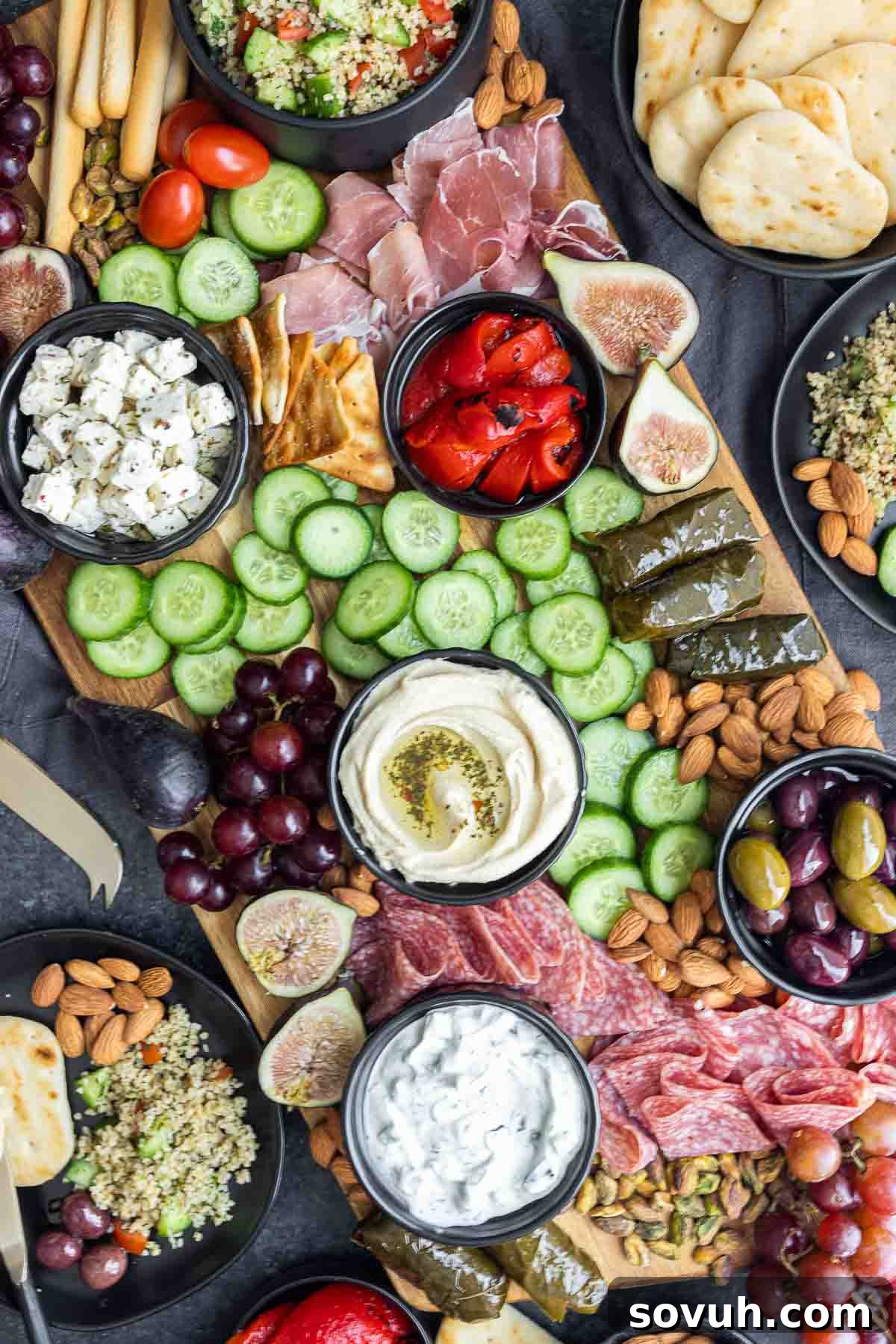 Abundant Mediterranean Mezze Platter on a large wooden board, showcasing a variety of bite-sized fruits and vegetables