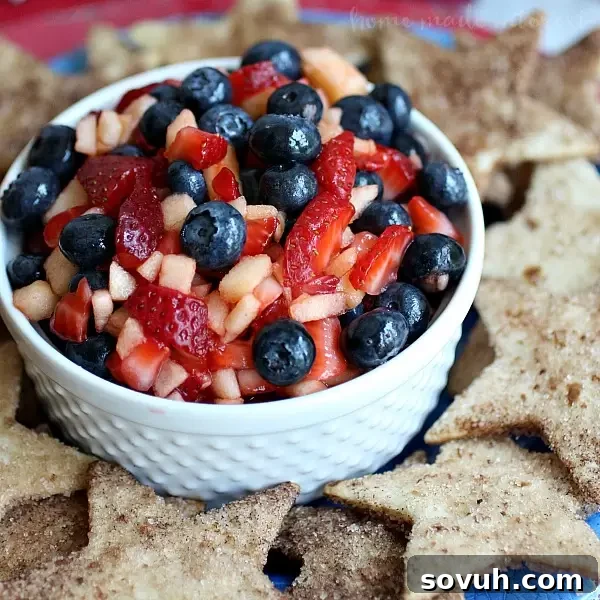 Overhead shot of patriotic Summer Fruit Salsa with red, white, and blue fruits and star-shaped cinnamon chips, symbolizing a festive holiday spread.