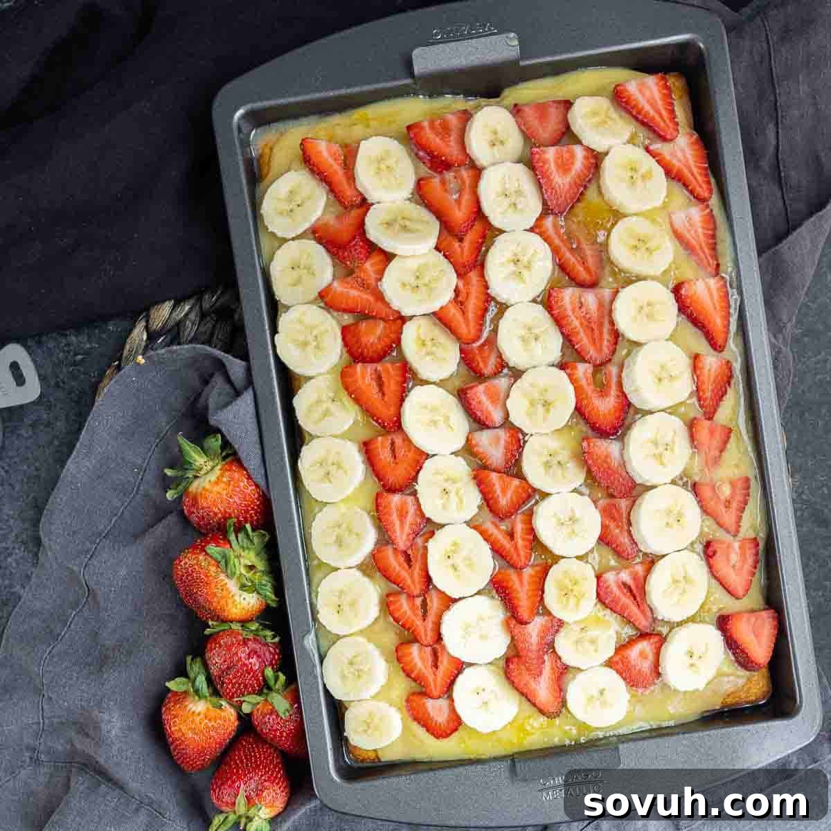 strawberries and banana sliced in rows on top of Banana Split Cake