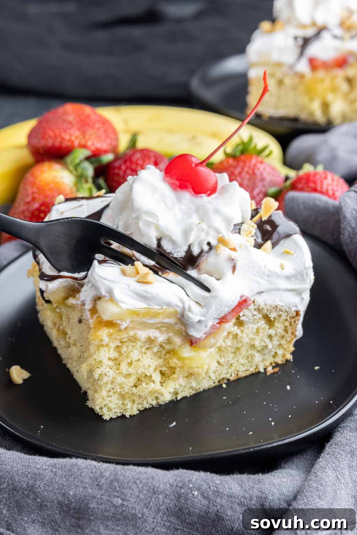 fork going into Banana Split Cake slice on black plate