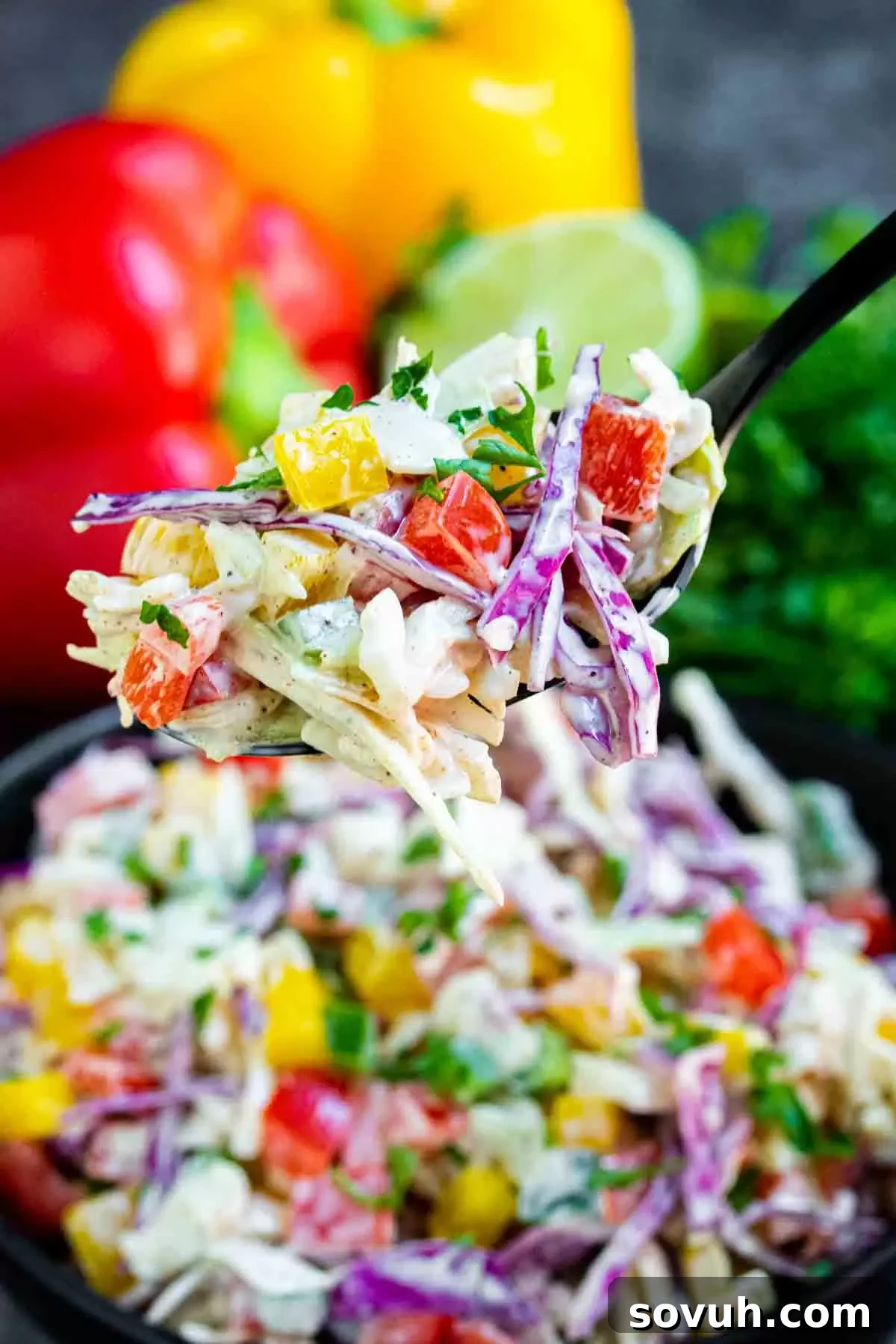 Close-up of Spicy Jalapeno Coleslaw on a black fork, highlighting the texture of the cabbage and the creamy dressing, ready for a delicious bite.