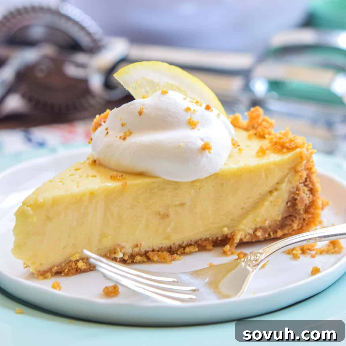 Zesty Lemon Icebox Pie 2 A slice of creamy Lemon Icebox Pie with a fork resting on the plate, ready to be enjoyed. The pie has a golden graham cracker crust and a vibrant yellow lemon filling.