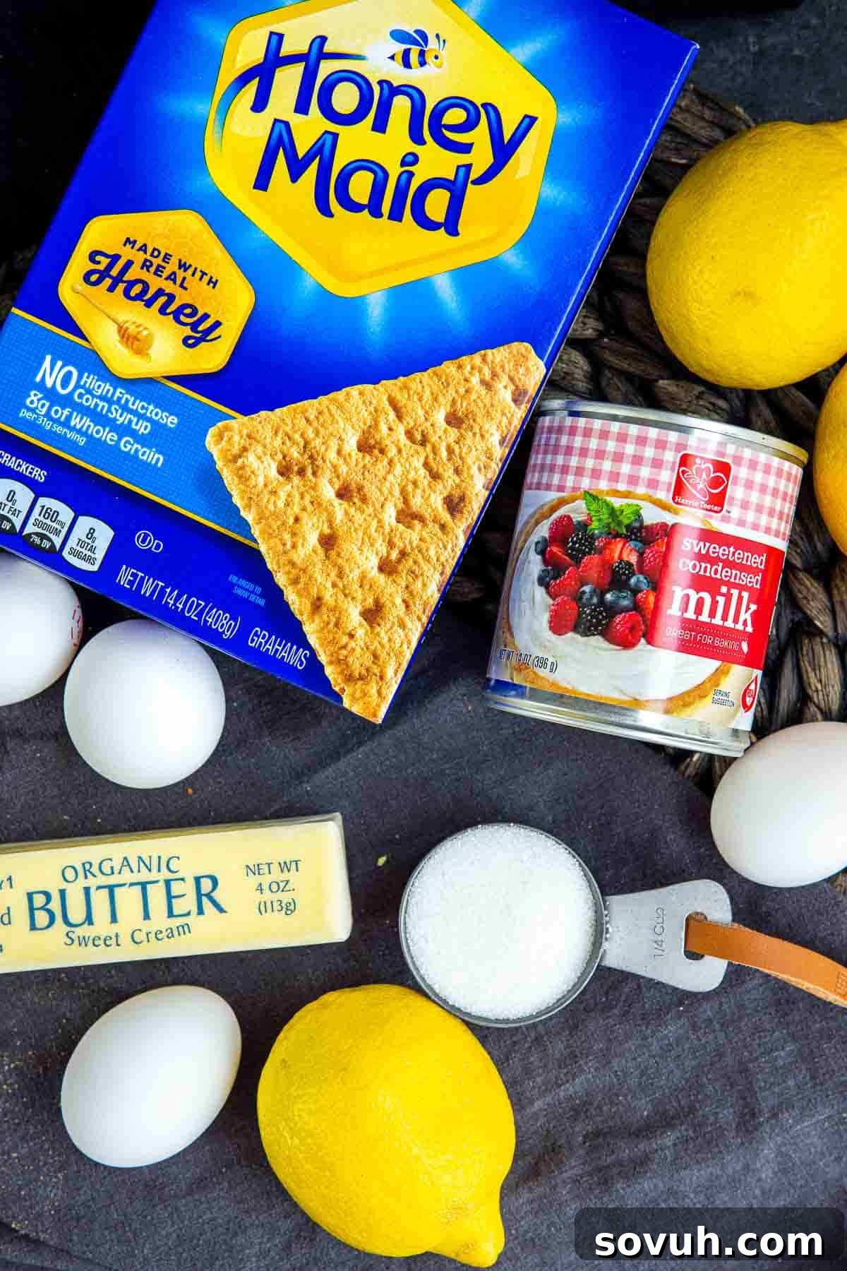 Zesty Lemon Icebox Pie 3 All the fresh ingredients laid out on a table to make a Lemon Icebox Pie, including lemons, graham cracker crumbs, eggs, butter, and sweetened condensed milk.